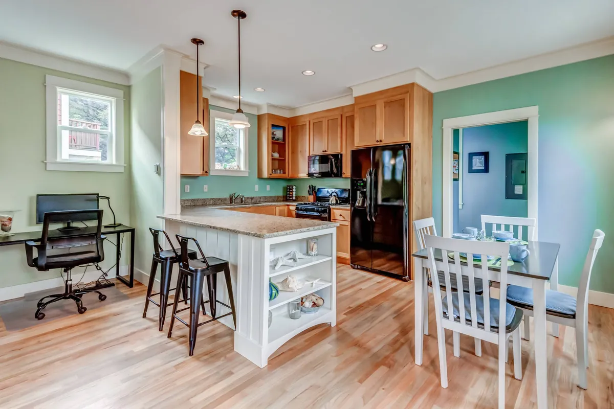 A spacious, open dining and kitchen area with an island counter and large dining table set for a meal. The space features warm lighting and comfortable seating, perfect for communal gatherings, cooking together, and sharing laughter after a day of adventure.