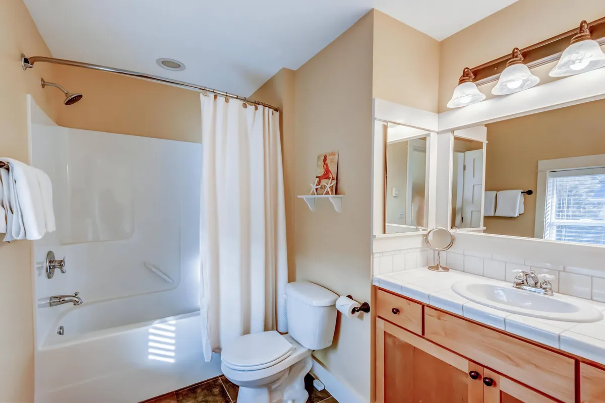 A bright, refreshed bathroom featuring a modern vanity, sleek light fixtures, and a gleaming bathtub. The setup is ideal for relaxing baths or rejuvenating showers, reflecting the ensuite comfort highlighted in the section.