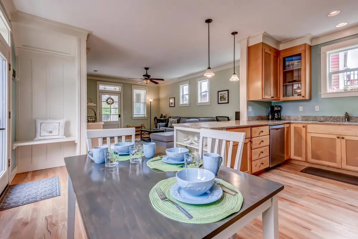A bright, inviting space where a dining table is set for breakfast, adjacent to a modern kitchen area equipped with contemporary appliances. Comfortable seating is included, and the room is infused with natural light, offering views that hint at scenic surroundings.
