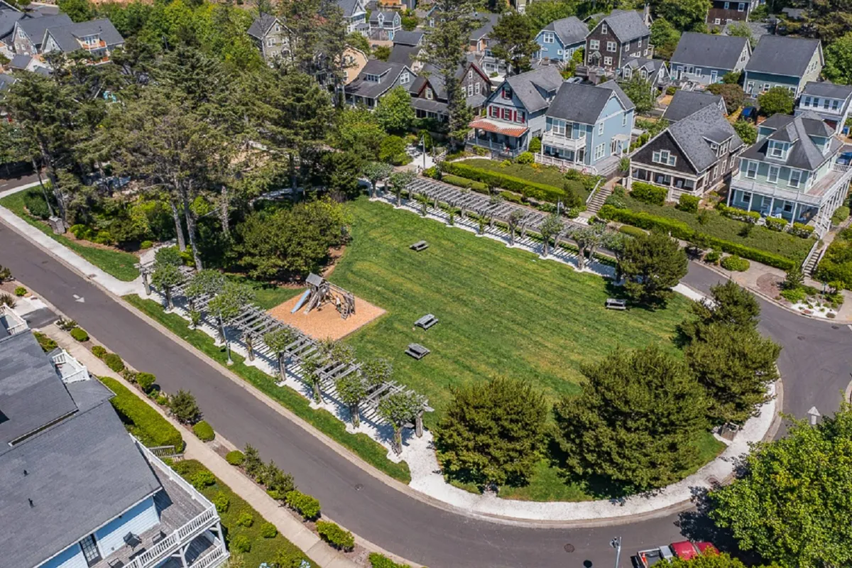 A cheerful playground set amidst manicured lawns, with children playing on equipment, surrounding homes in the background, and winding pathways inviting strolls. The lively mood reflects community gatherings and outdoor recreation.